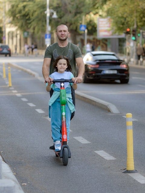 man and his kid riding electric scooter